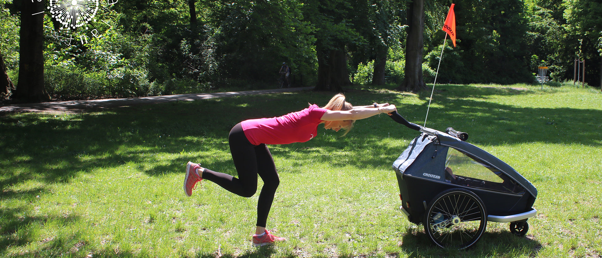 Woman in standing mountain climber position with one knee up using Croozer bike trailer for support in park